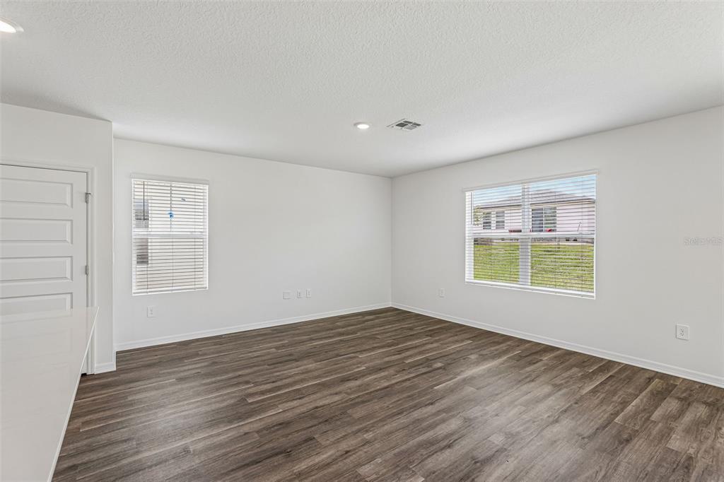 An empty room with white walls, wood-look flooring, and two windows with blinds — 5614 BROOK LANE, HAINES CITY, FL