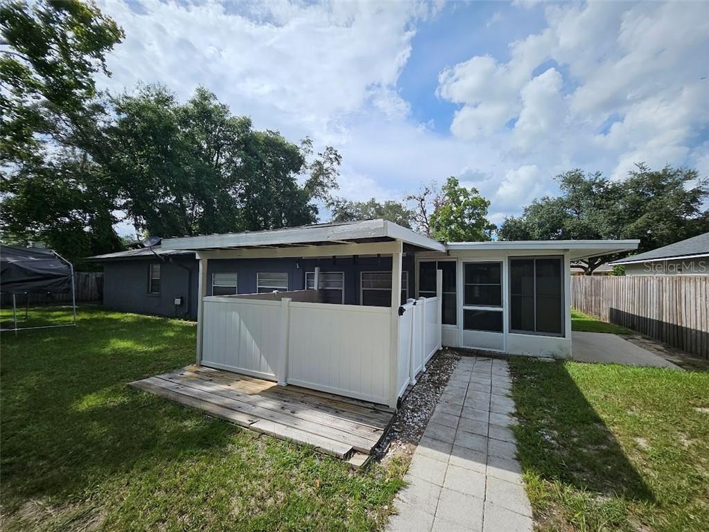 A backyard view shows a house with a screened porch, a wooden deck, and white fencing — 1680 JAGUAR CIRCLE, APOPKA, FL