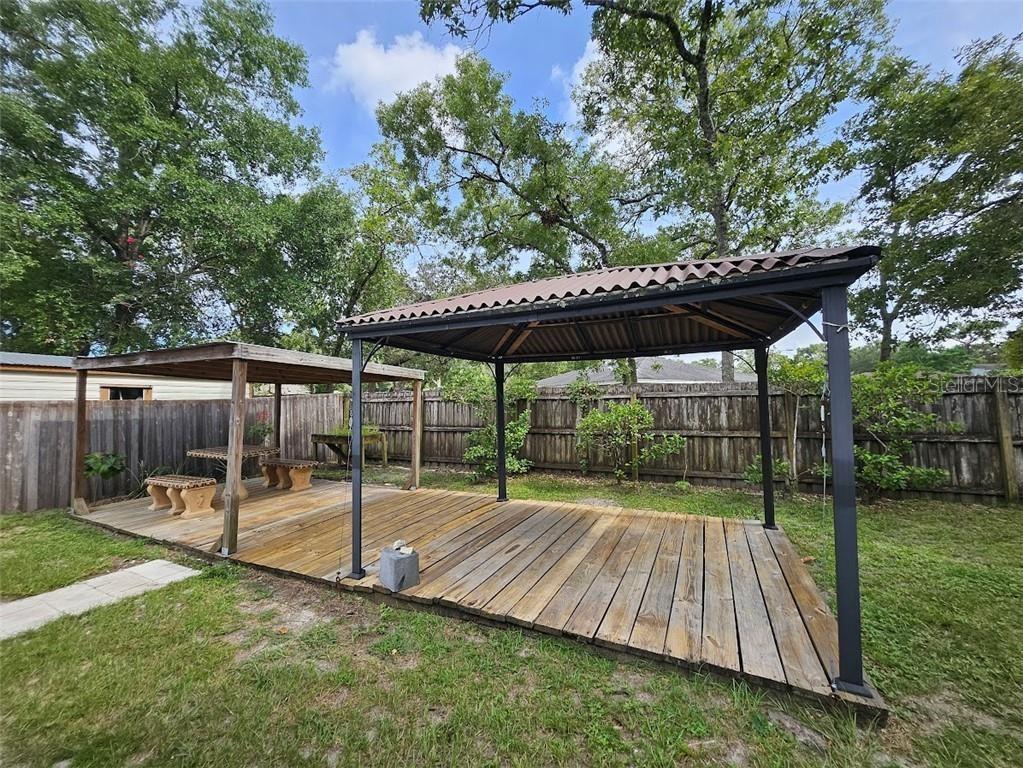 A wooden deck features two covered outdoor structures with a metal roof and seating area — 1680 JAGUAR CIRCLE, APOPKA, FL
