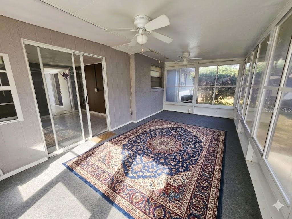 A sunroom features a large patterned area rug, two ceiling fans, and sliding glass doors — 1680 JAGUAR CIRCLE, APOPKA, FL