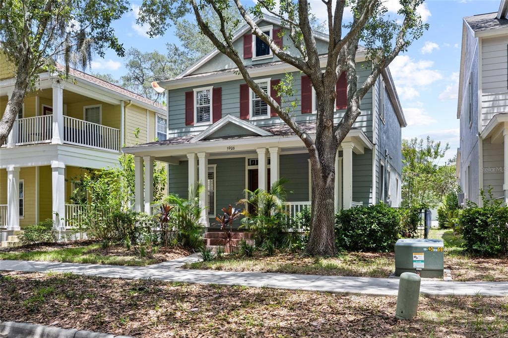 A two-story house with green siding, red shutters, and a front porch sits behind trees — 5906 BEACONPARK STREET, LITHIA, FL