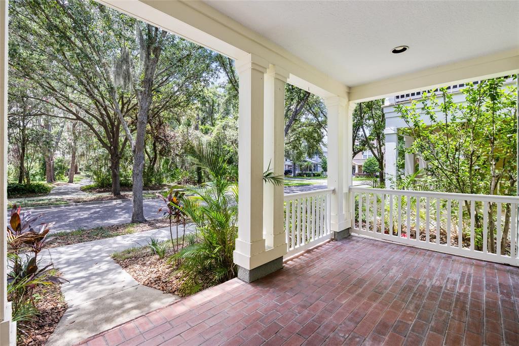 A covered front porch features a red brick floor, white railings, and square support columns — 5906 BEACONPARK STREET, LITHIA, FL