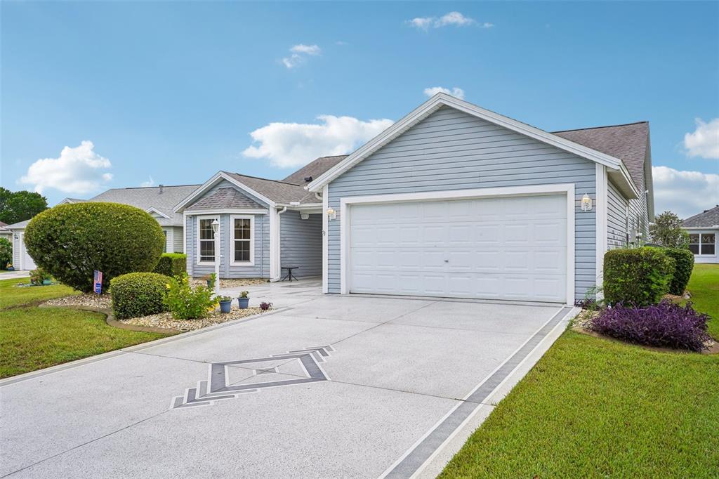 A blue single-story house with a two-car garage and a decorative concrete driveway — 2608 CASSO COURT, THE VILLAGES, FL