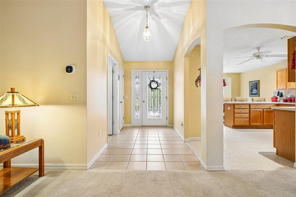 A foyer with tile flooring leads to a front door with a decorative glass insert — 2608 CASSO COURT, THE VILLAGES, FL