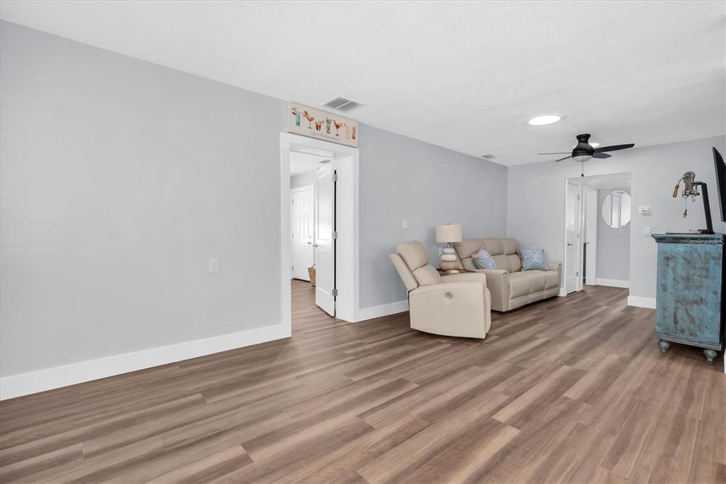 A living room features light gray walls, wood-look flooring, a recliner, and a sofa — 528 77TH AVENUE, ST PETE BEACH, FL