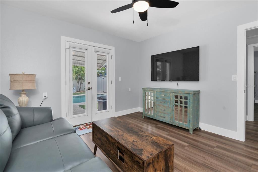 A living room features a gray sofa, wood coffee table, teal media console, and glass doors — 528 77TH AVENUE, ST PETE BEACH, FL