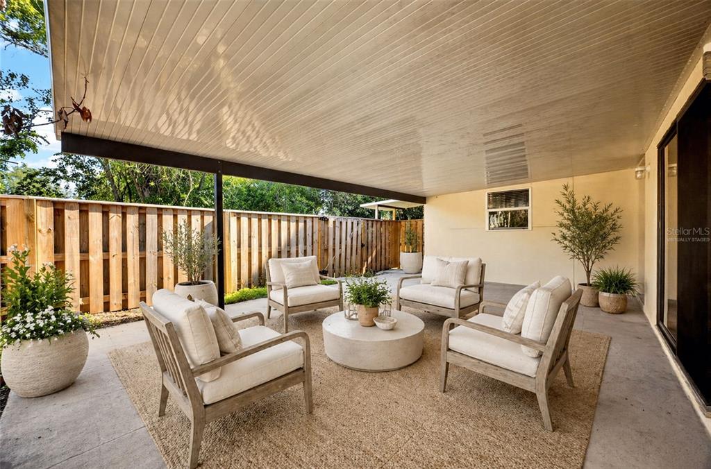 A covered concrete patio features four armchairs arranged around a round coffee table on a rug — 2906 ASH DRIVE, LEESBURG, FL