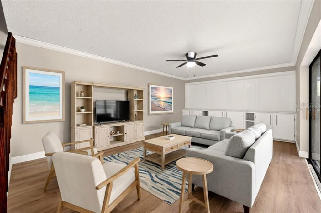 A living room with light wood floors, a sectional sofa, two armchairs, and built-in cabinetry — 2906 ASH DRIVE, LEESBURG, FL
