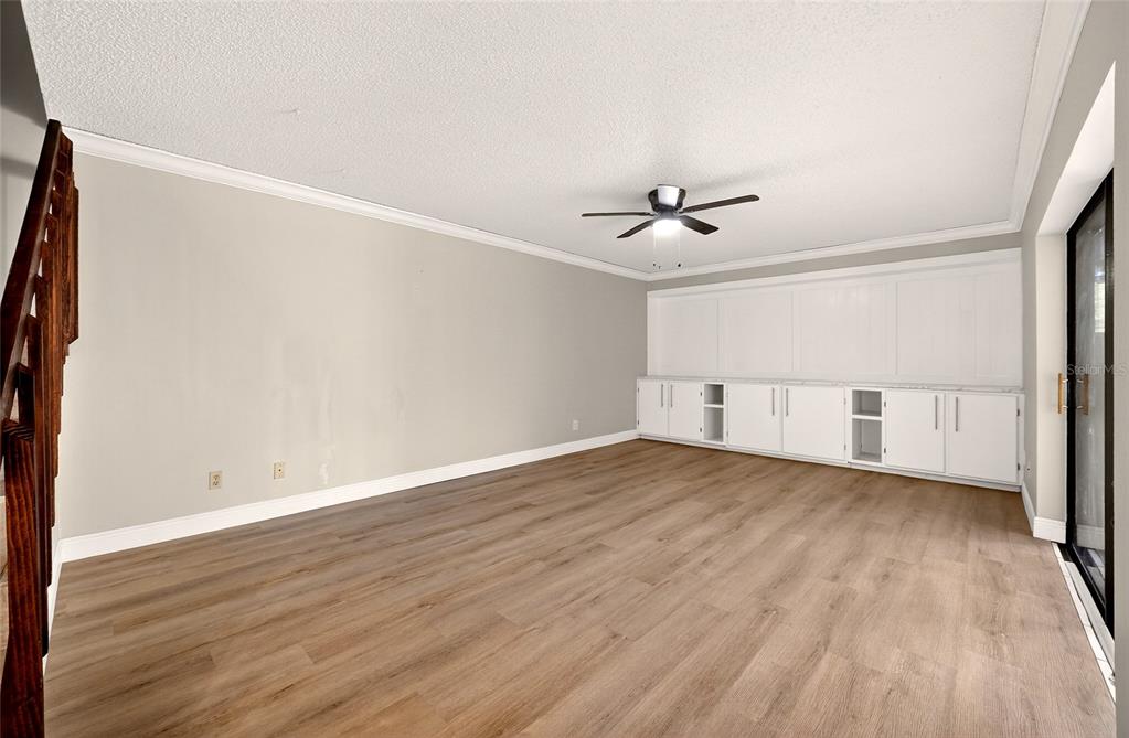 A living room with light gray walls, wood-look flooring, a ceiling fan, and white cabinetry — 2906 ASH DRIVE, LEESBURG, FL