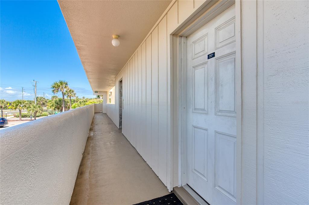 An outdoor balcony walkway leads to a white door labeled 217 at a multi-story building — 935 OCEAN SHORE BOULEVARD UNIT 2170, ORMOND BEACH, FL
