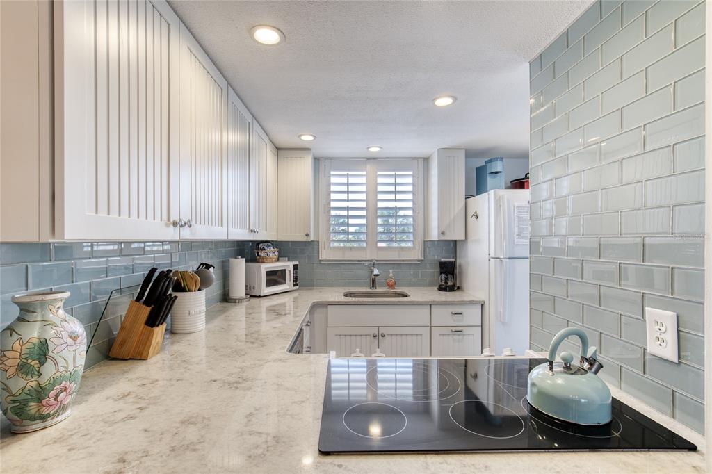 A kitchen features white beadboard cabinets, light blue subway tile backsplash, and speckled stone countertops — 935 OCEAN SHORE BOULEVARD UNIT 2170, ORMOND BEACH, FL