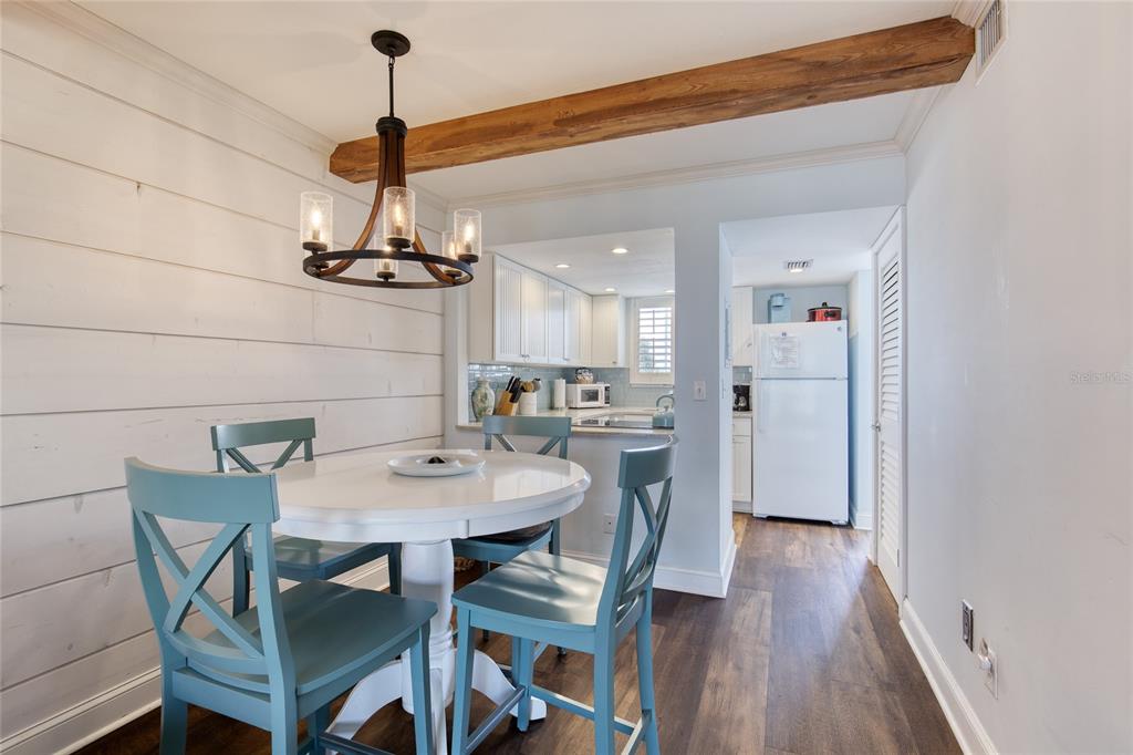 A dining area with a white table, blue chairs, shiplap walls, and a wooden ceiling beam — 935 OCEAN SHORE BOULEVARD UNIT 2170, ORMOND BEACH, FL