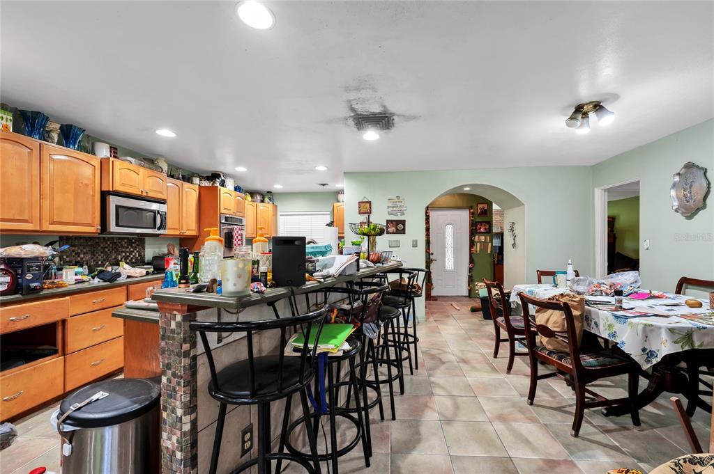 A kitchen with wood cabinets, a breakfast bar with stools, and a dining area — 3126 S OSCEOLA AVENUE, ORLANDO, FL