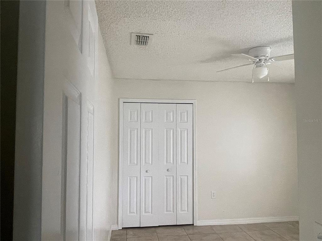 A room with white walls, a ceiling fan, a tiled floor, and white closet doors — 820 BLANC COURT, KISSIMMEE, FL