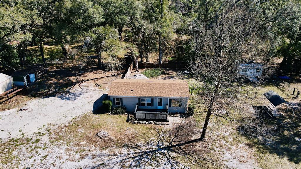A tan mobile home features a wooden deck, dark shutters, and a propane tank outside — 2665, 2639 E HWY 466, OXFORD, FL