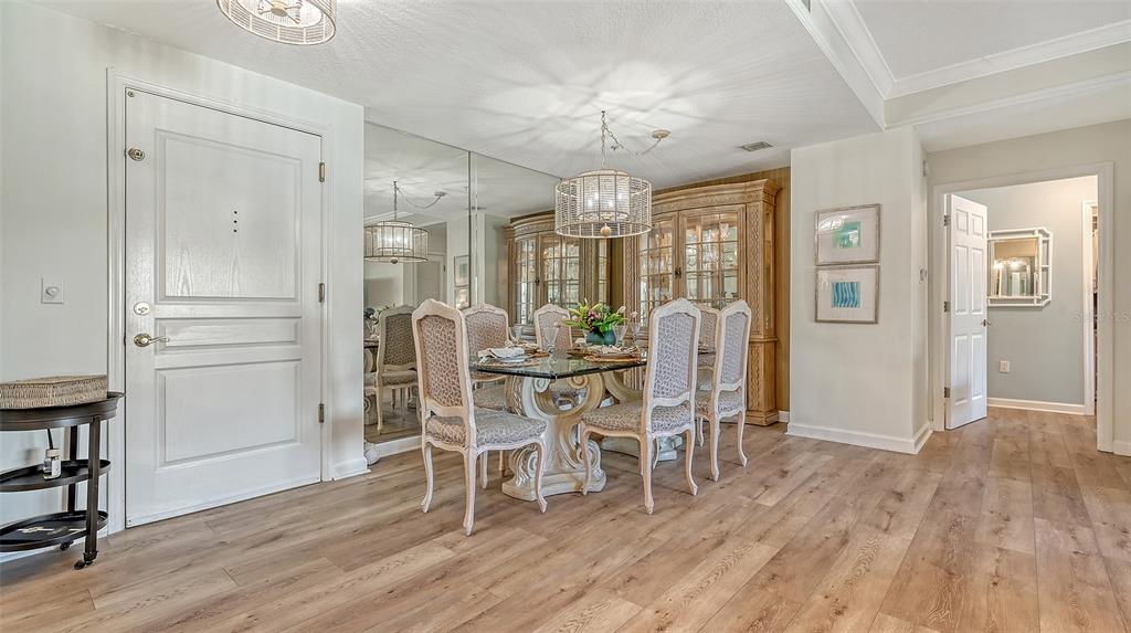 A dining room features a glass-topped table, upholstered chairs, a mirrored wall, and wood flooring — 750 N TAMIAMI TRAIL UNIT 304, SARASOTA, FL