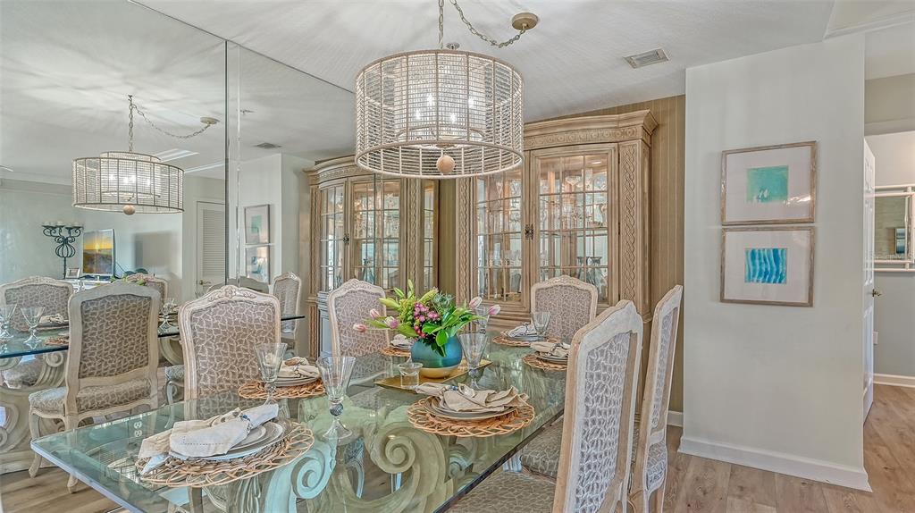 A dining room features a glass-topped table, upholstered chairs, a large hutch, and mirrored walls — 750 N TAMIAMI TRAIL UNIT 304, SARASOTA, FL