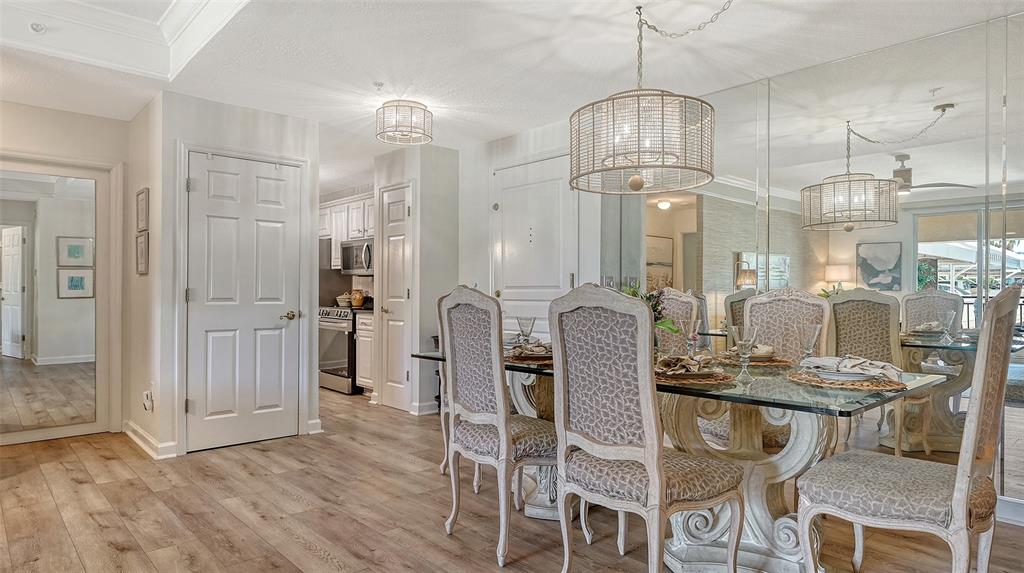 A dining room features a glass-topped table, upholstered chairs, mirrored walls, and wood-look flooring — 750 N TAMIAMI TRAIL UNIT 304, SARASOTA, FL