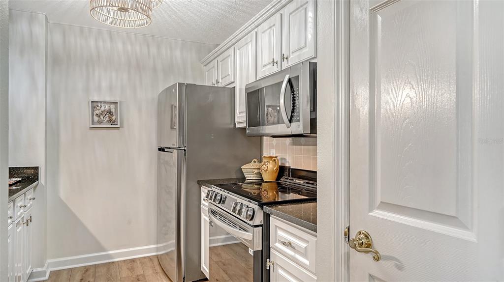 A kitchen features white cabinets, stainless steel appliances, dark countertops, and light wood-look flooring — 750 N TAMIAMI TRAIL UNIT 304, SARASOTA, FL