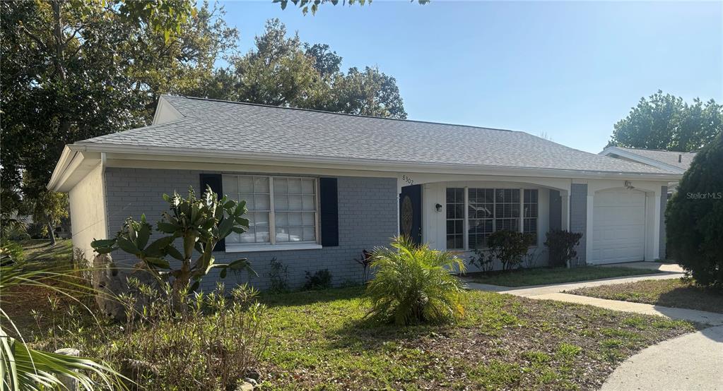 A single-story gray brick house with a shingled roof and an attached garage — 8302 SPLIT RAIL LANE, HUDSON, FL