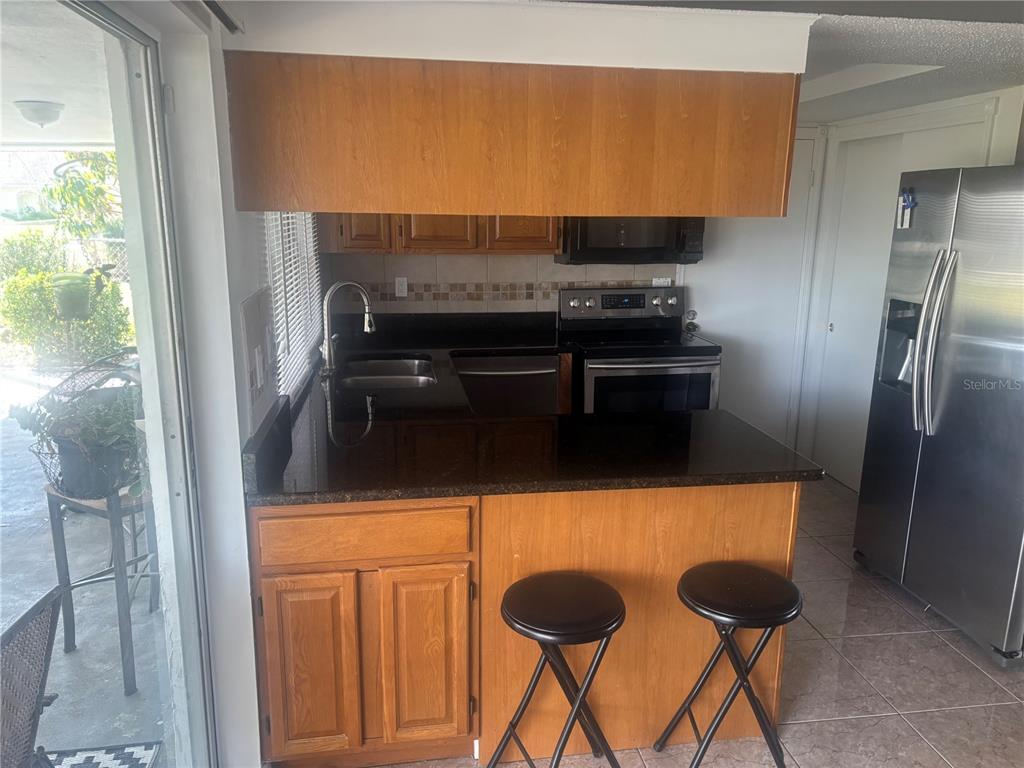A kitchen features wood cabinets, dark countertops, stainless steel appliances, and a breakfast bar — 8302 SPLIT RAIL LANE, HUDSON, FL