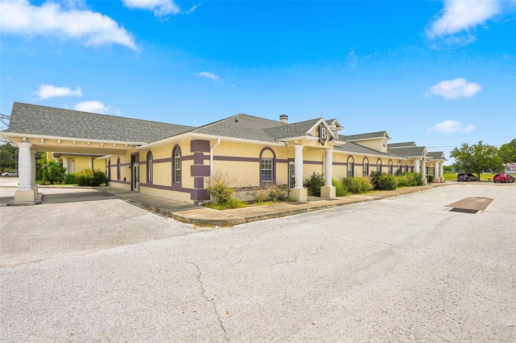 A single-story commercial building with a covered entrance, yellow stucco walls, and a shingled roof — 224 MARINER BOULEVARD, SPRING HILL, FL