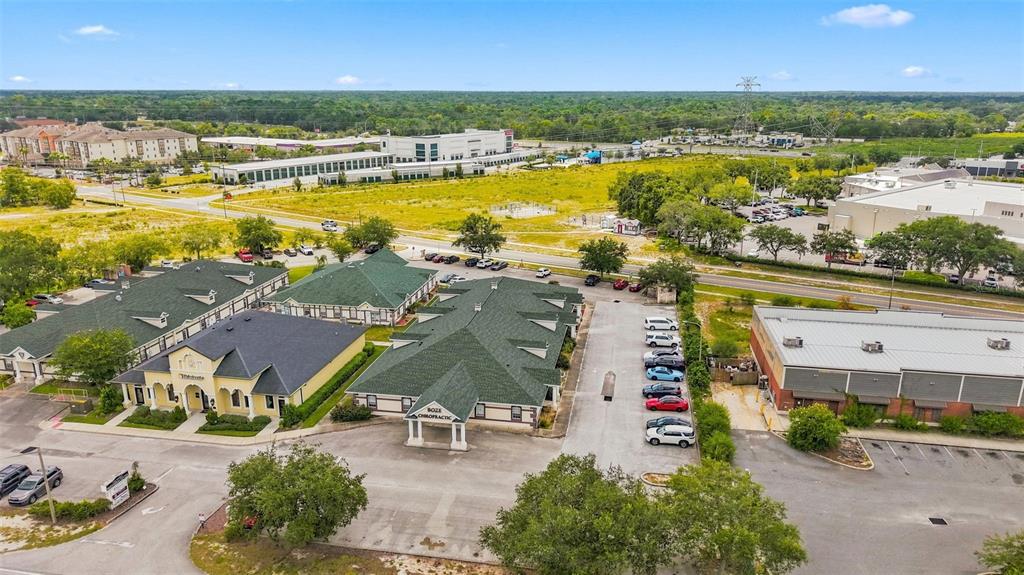 An aerial view shows commercial buildings with green roofs, parking lots, and surrounding landscape — 224 MARINER BOULEVARD, SPRING HILL, FL