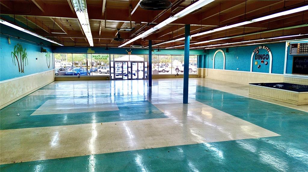 An empty commercial space features teal and white flooring, exposed ceiling beams, and bingo signage — 1091 W MAIN STREET, AVON PARK, FL