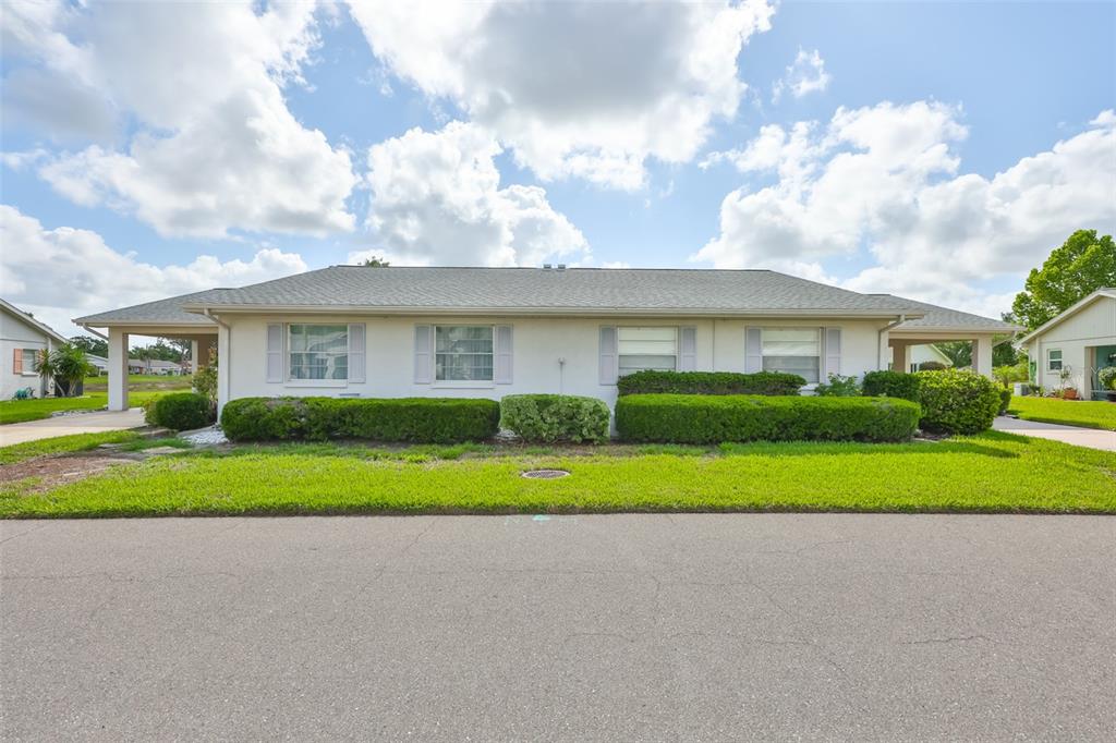 A single-story duplex with a light-colored exterior, a shingled roof, and manicured front landscaping — 109 GLENDOWER CIRCLE, SUN CITY CENTER, FL
