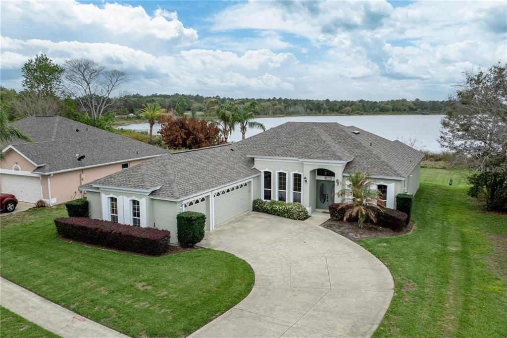 An aerial view of a single-story house with a curved driveway and a lake view — 3804 BAYSHORE CIRCLE, TAVARES, FL
