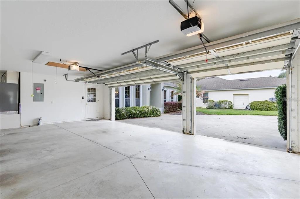 An open two-car garage with concrete floors, white walls, and a view of the driveway — 3804 BAYSHORE CIRCLE, TAVARES, FL
