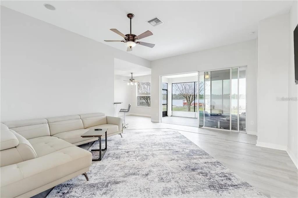 A living room with a white sectional sofa, a patterned rug, and sliding glass doors — 3804 BAYSHORE CIRCLE, TAVARES, FL