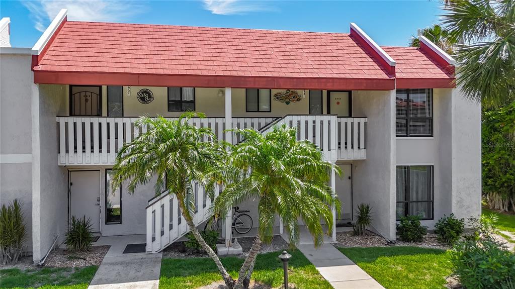 A covered balcony features a small table, two chairs, and a view of the water — 1801 GULF DRIVE N UNIT 293, BRADENTON BEACH, FL