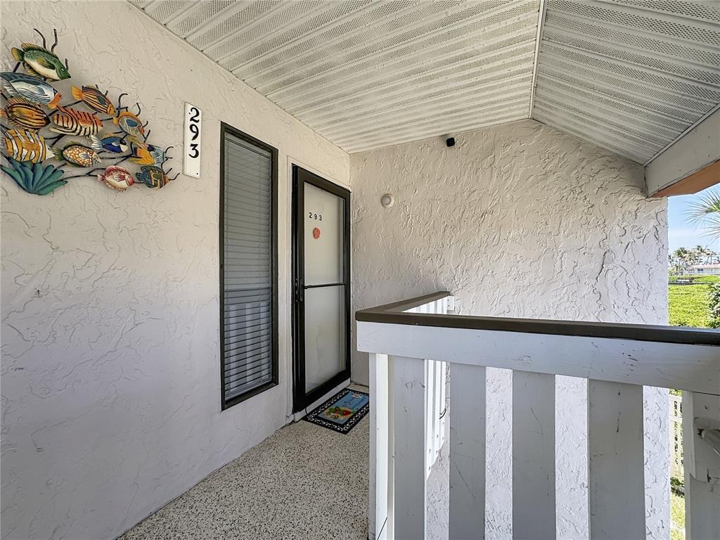 A covered balcony features a small table, a chair, and a view of the water — 1801 GULF DRIVE N UNIT 293, BRADENTON BEACH, FL
