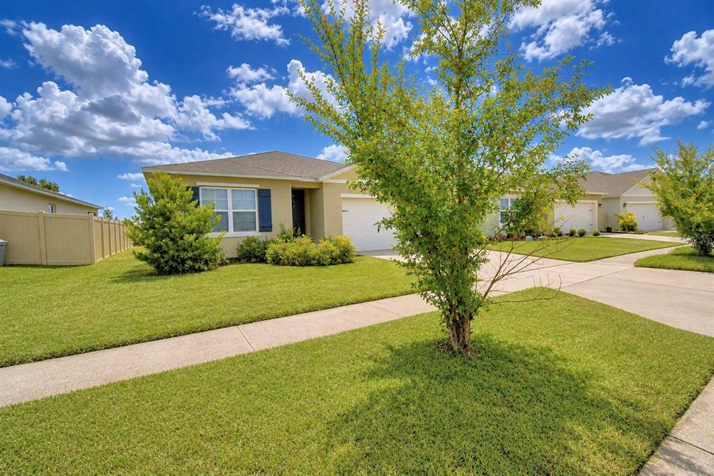 A single-story house with a tan exterior, a white garage door, and a green lawn — 5628 SILTSTONE STREET, LAKELAND, FL