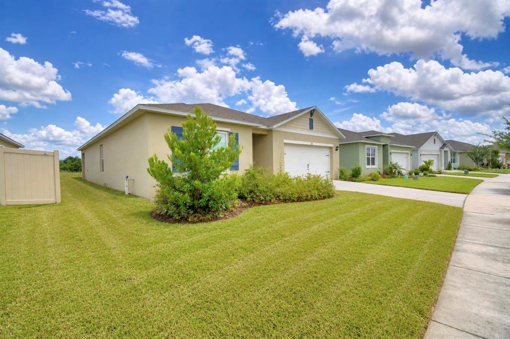 A single-story house with a tan exterior, blue shutters, and a two-car garage — 5628 SILTSTONE STREET, LAKELAND, FL