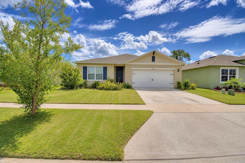 A single-story suburban house with a tan exterior, a two-car garage, and a manicured lawn — 5628 SILTSTONE STREET, LAKELAND, FL
