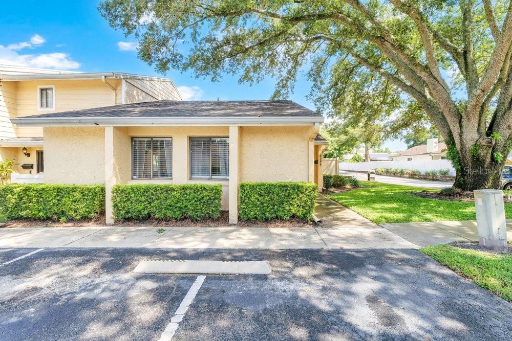 A single-story tan stucco building with a shingled roof and a manicured hedge in front — 5395 EMERALD ISLE DRIVE UNIT 1011, ORLANDO, FL