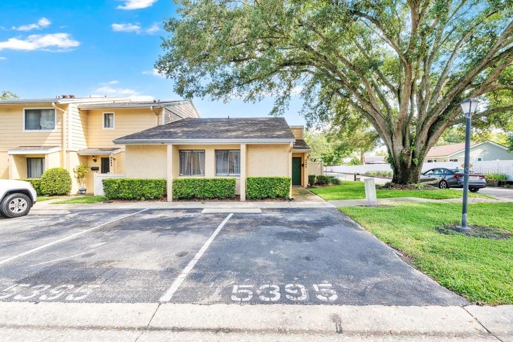 A single-story tan townhouse with a parking space marked 5395 in the foreground — 5395 EMERALD ISLE DRIVE UNIT 1011, ORLANDO, FL