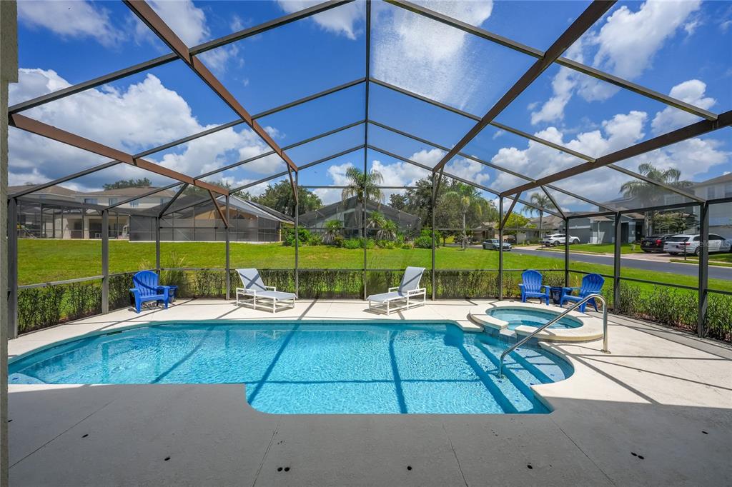 A screened-in swimming pool and spa with lounge chairs on a concrete patio — 358 LANCASTER DR, DAVENPORT, FL