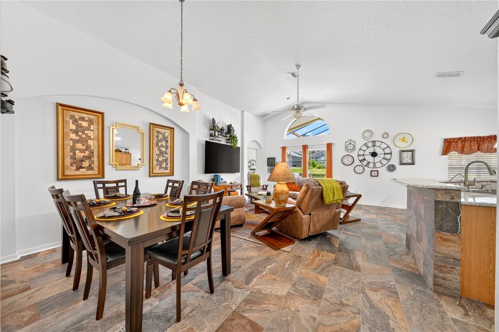An open-concept living and dining area features tile flooring, vaulted ceilings, and a kitchen island — 358 LANCASTER DR, DAVENPORT, FL