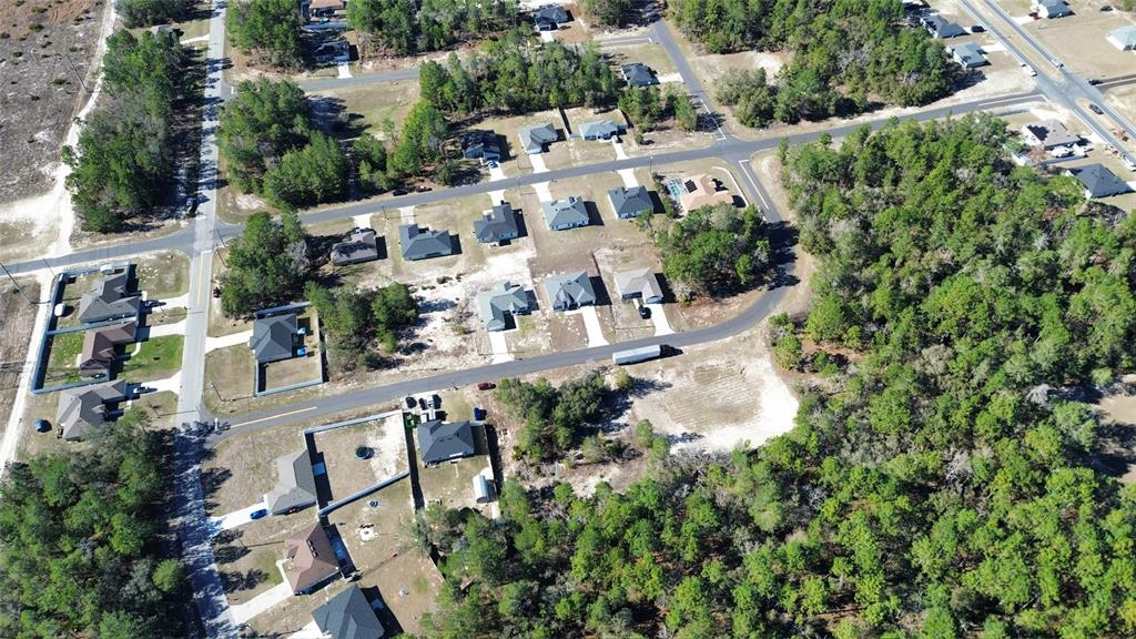 An aerial view shows a suburban neighborhood with single-family homes surrounded by wooded areas — LOT 11 MARION OAKS PASS, OCALA, FL
