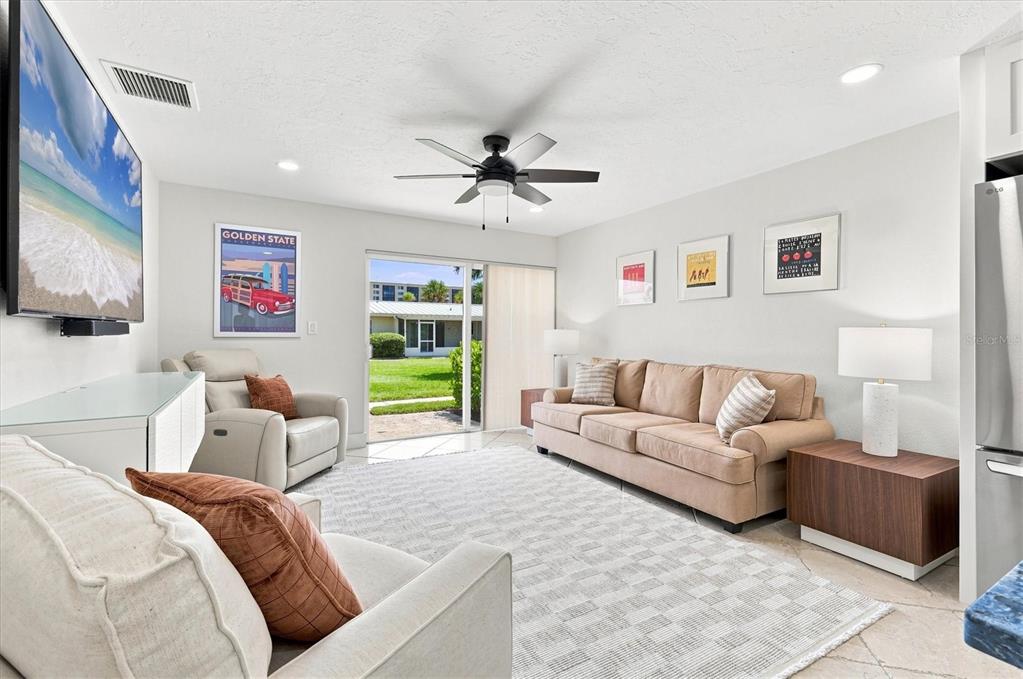 A living room features a beige sofa, two armchairs, a television, and a sliding glass door — 5830 MIDNIGHT PASS ROAD UNIT 18, SARASOTA, FL