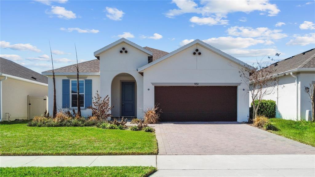 A single-story house with a white stucco exterior, a two-car garage, and blue shutters — 951 VINEYARD RIDGE ROAD, MINNEOLA, FL