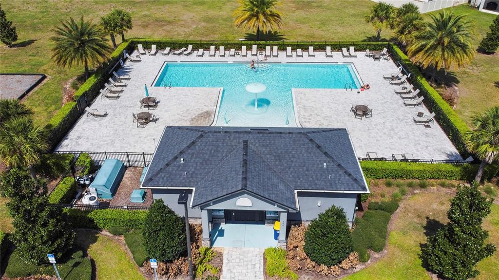An aerial view shows a swimming pool with a fountain and a clubhouse building — 951 VINEYARD RIDGE ROAD, MINNEOLA, FL