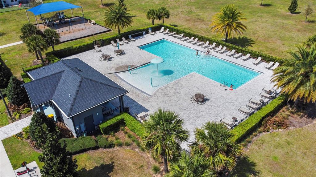 An aerial view shows a swimming pool with a sun shelf, patio, and adjacent playground — 951 VINEYARD RIDGE ROAD, MINNEOLA, FL