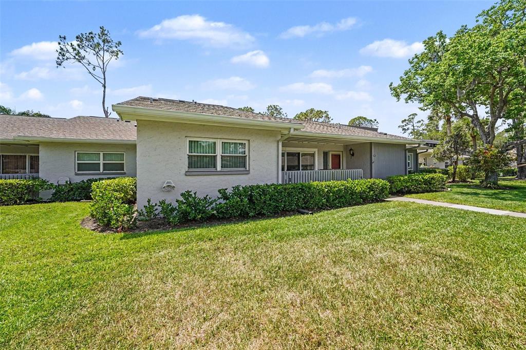 A single-story residential building with a beige stucco exterior, a shingled roof, and green landscaping — 230 BALSAM DRIVE, OLDSMAR, FL