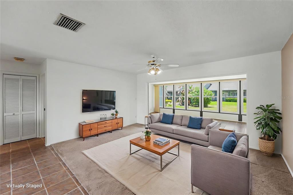 A living room with carpet, a sofa, a coffee table, and a large windowed wall — 230 BALSAM DRIVE, OLDSMAR, FL
