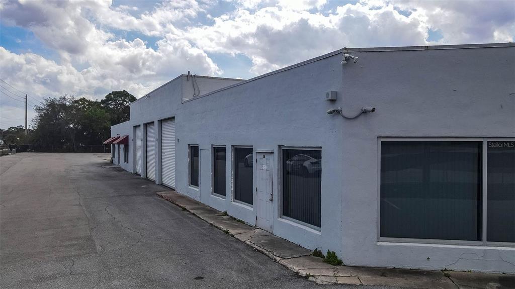 A low-rise, light-colored industrial building with multiple roll-up doors and windows along a paved lot — 415 ANGLE ROAD, FORT PIERCE, FL