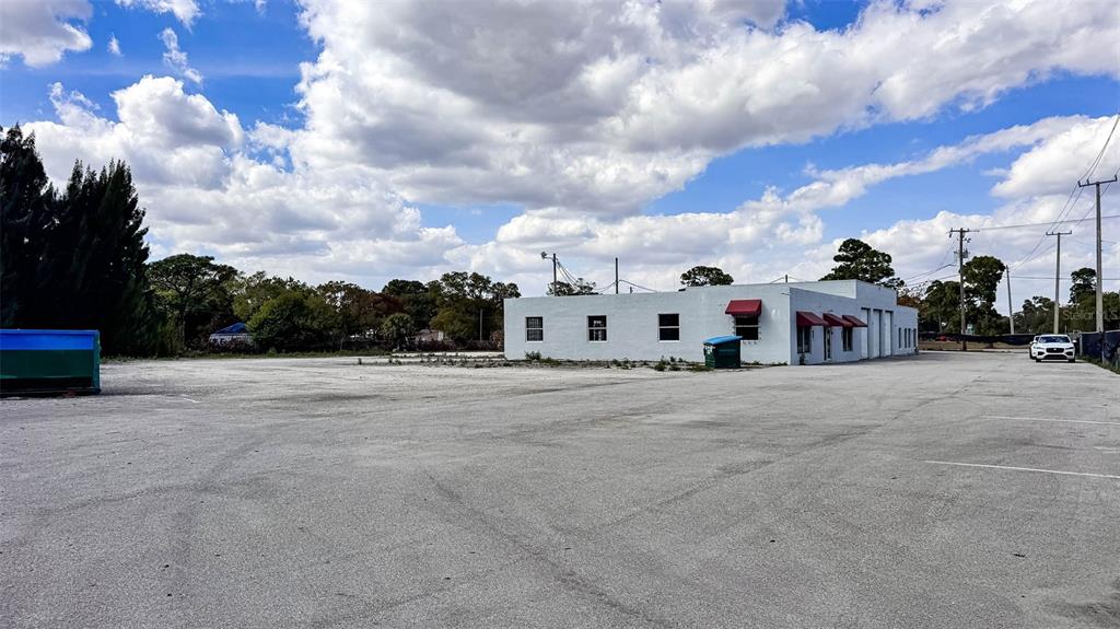 A white commercial building sits on a large, paved parking lot under a cloudy sky — 415 ANGLE ROAD, FORT PIERCE, FL